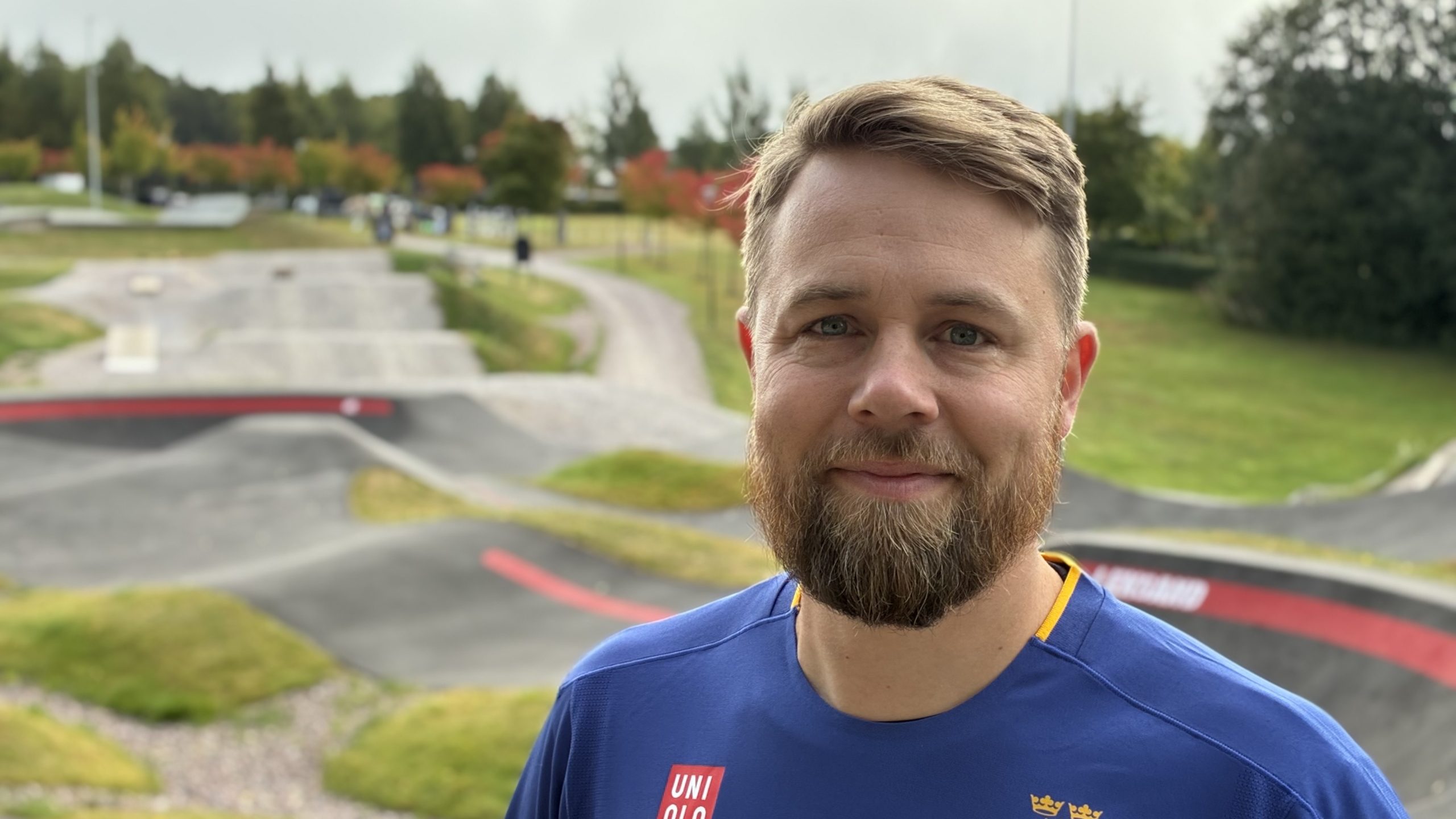 Porträttbild på man med blå SOK-kläder framför pumptrackbanan.