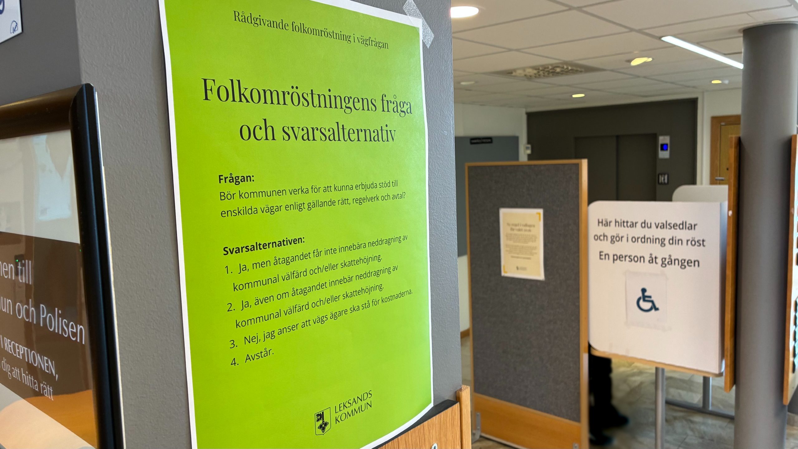 Bild inifrån en vallokal där ett grönt anslag med folkomröstningsfrågan syns störst i bilden.