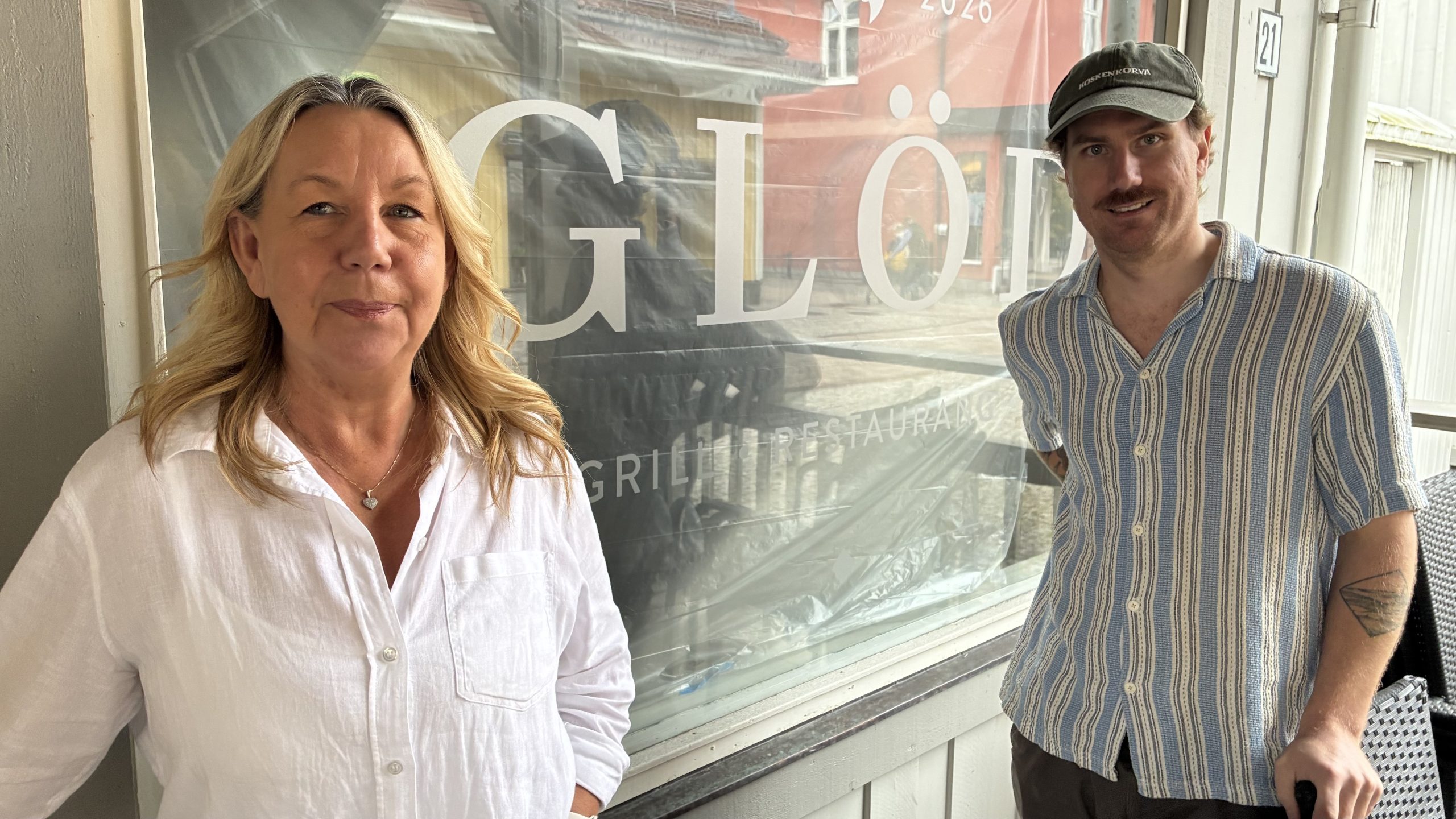 Cattis Kullgren och Robin Jobs framför ett skyltfönster med texten Glöd. Innanför fönstret syns fortfarande byggplasten.
