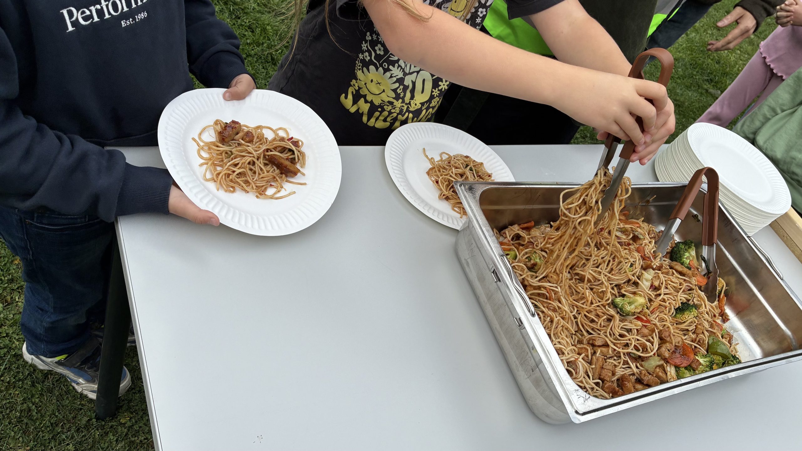 Skolmat serveras på papptallrikar av små barnhänder.
