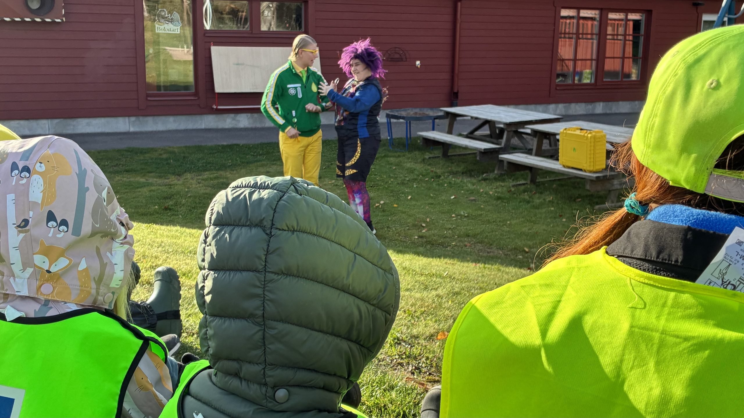 Luvorna på barnens bakhuvuden i förgrunden, samtidigt som de tittar på föreställningen på förskolans innergård.