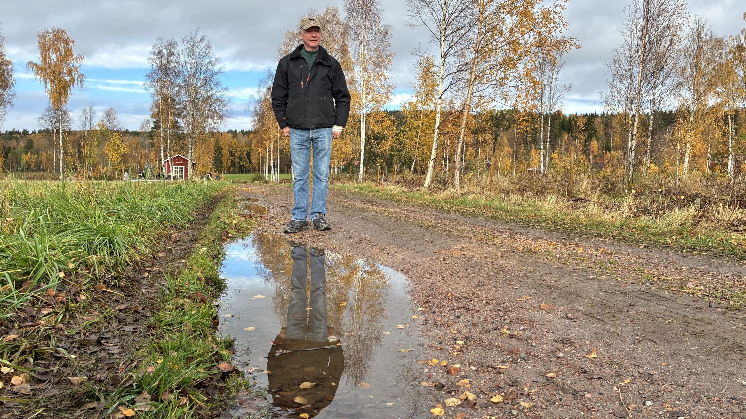 Göran Svensson vid en vattenpöl och ett stort däckmärke vid sidan av den lilla grusvägen.