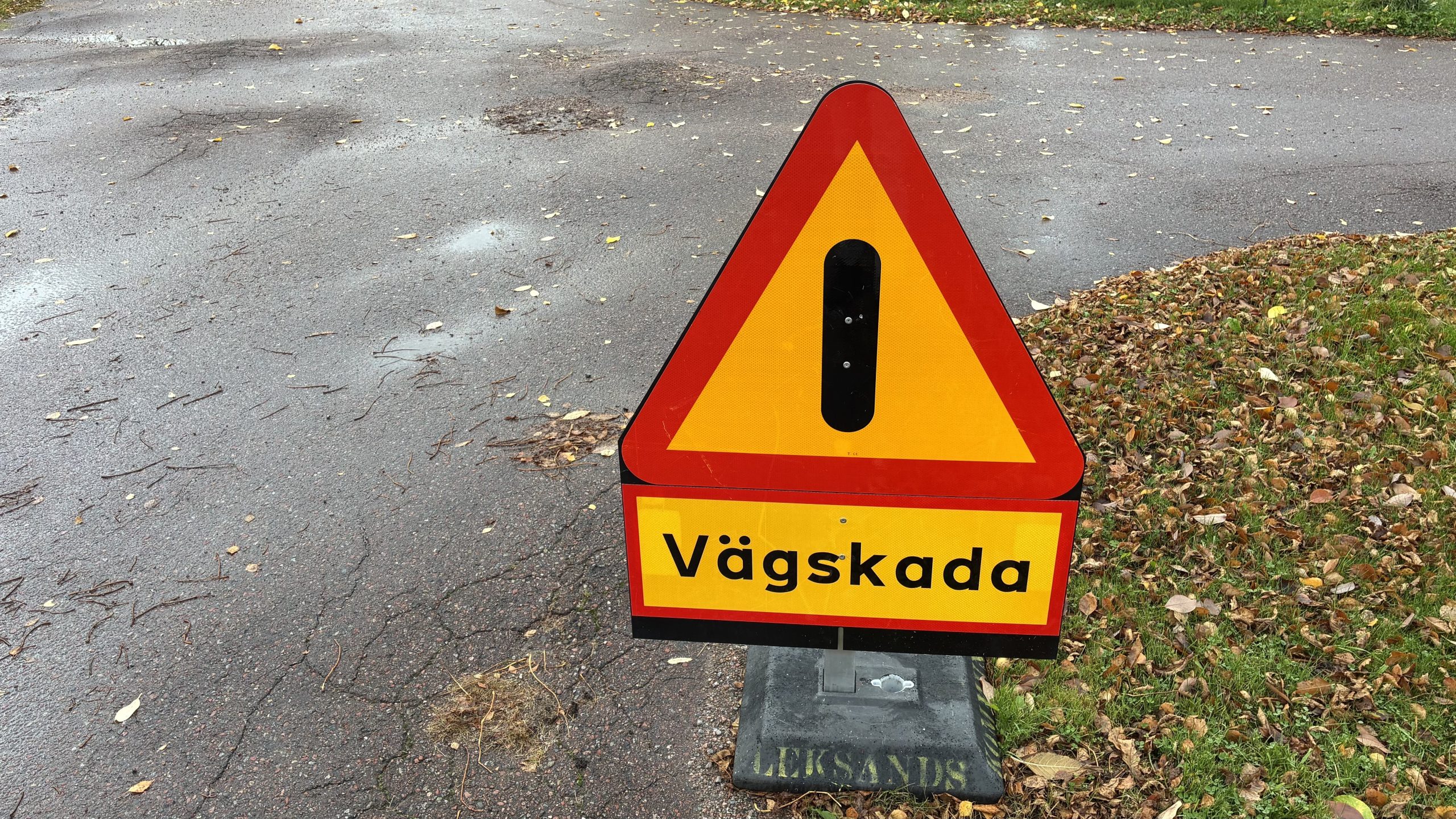 Närbild på en varningsskylt i trafiken som varnar för en vägskada.