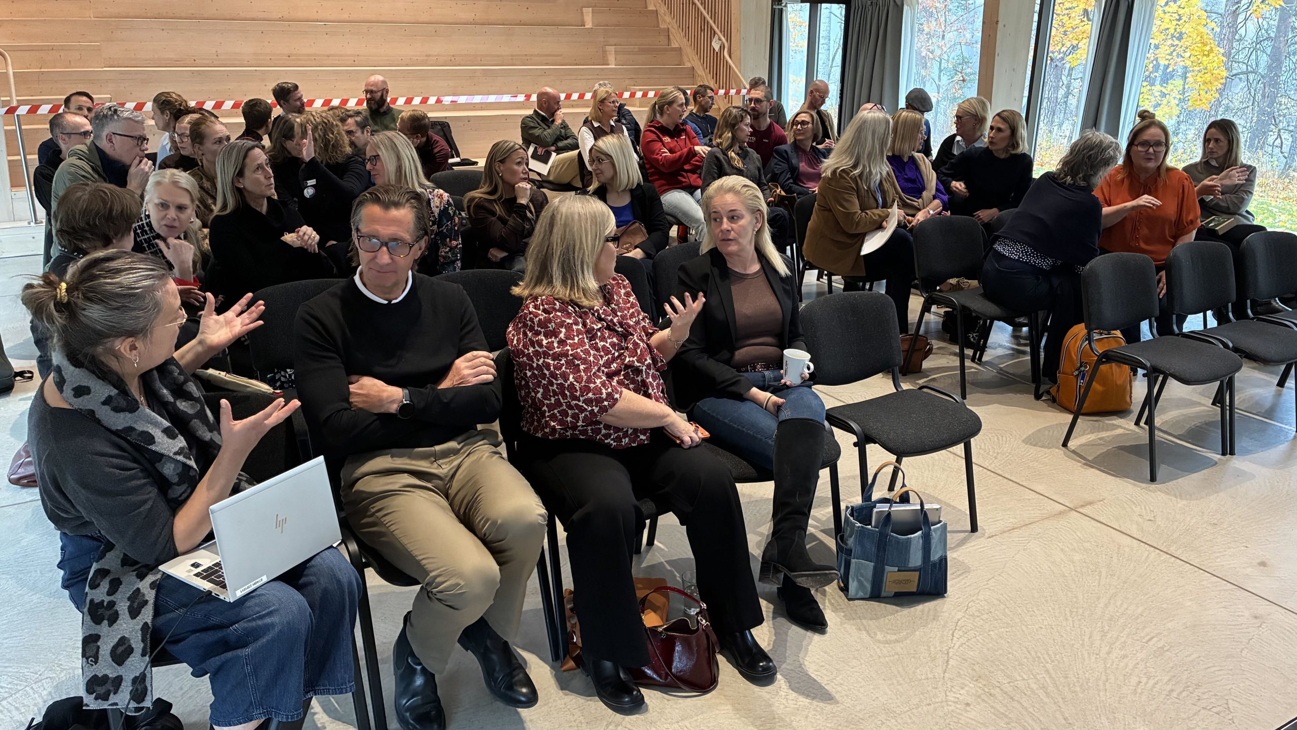 Gruppbild på ca 45 av deltagarna som sitter på stolar och diskuterar med varandra. Många har ett livligt kroppsspråk.