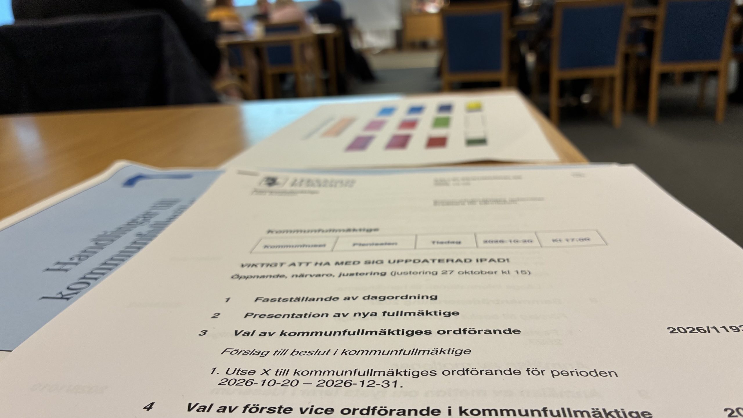 Närbild på ett kommunfullmäktigepapper där valen av ordförande är inzoomade. Fullmäktigesalen i bakgrunden.