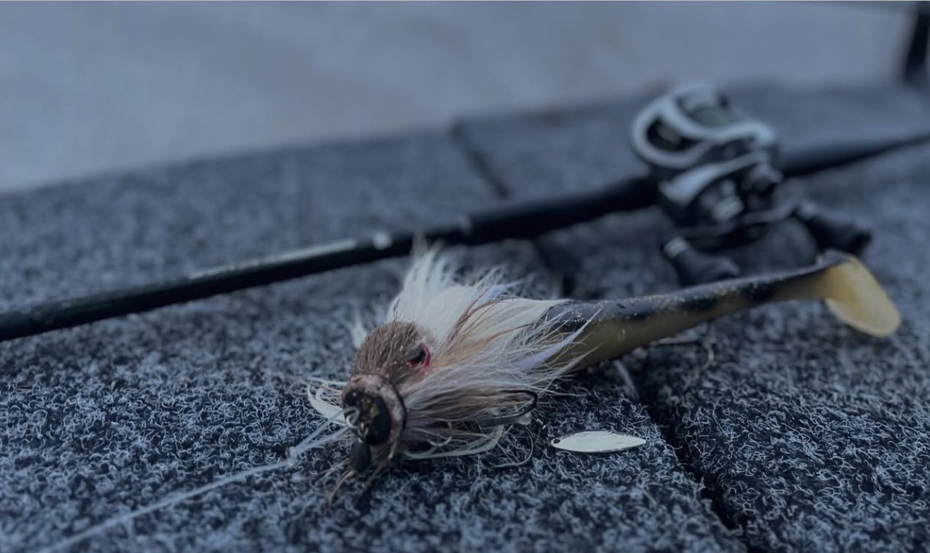 Närbild på ett hårigt fiskedrag med en gummijigg som liknar en abborre i färgerna.